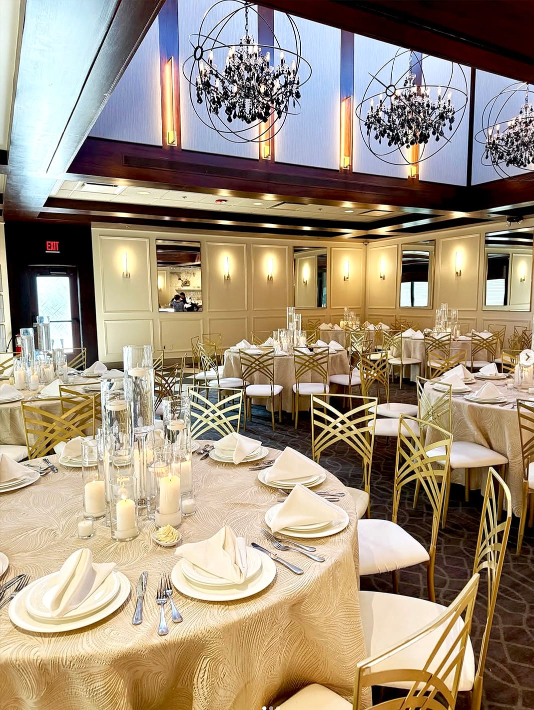 A beautifully set dining room with round tables and chandeliers