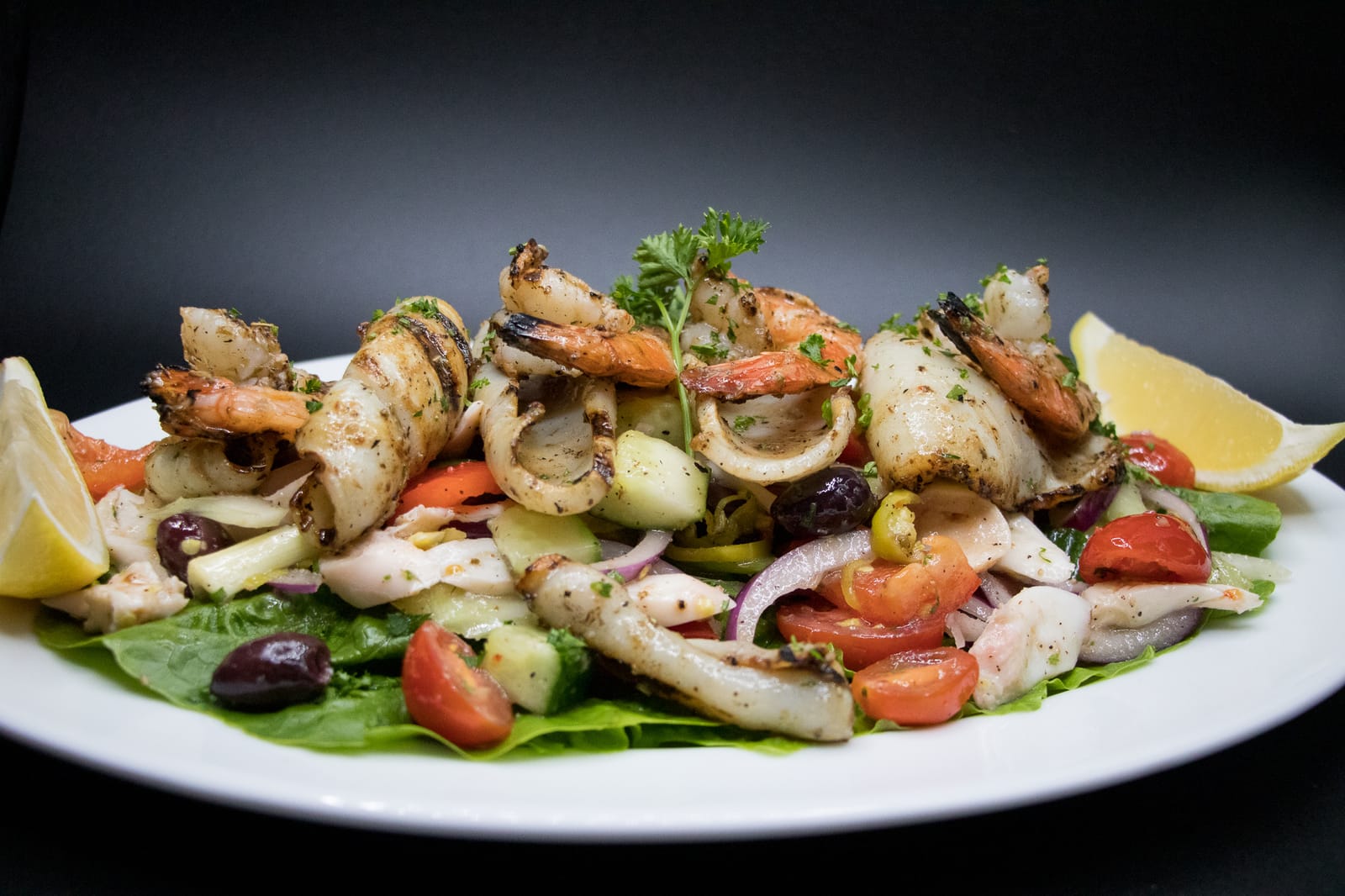 Grilled seafood salad with shrimp, calamari, olives and lemon