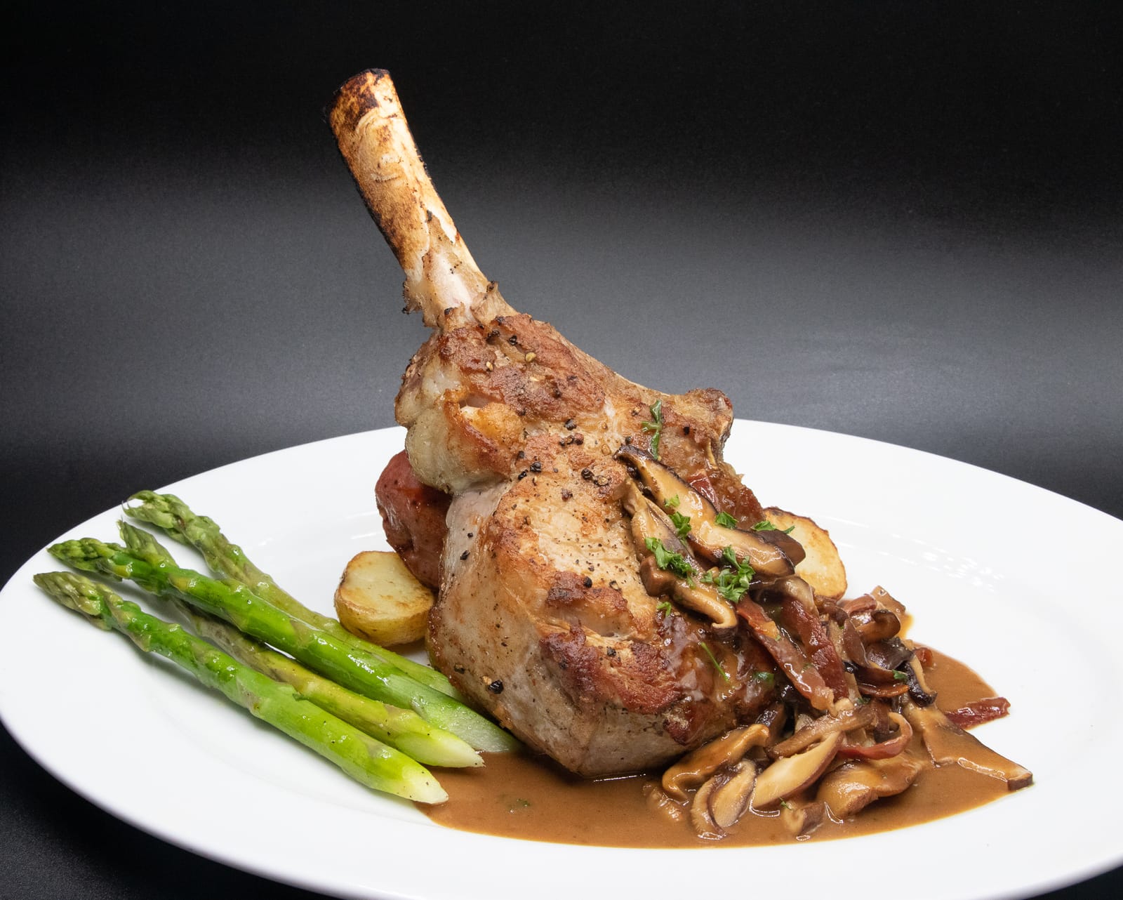 Grilled bone-in veal chop with asparagus and mushrooms